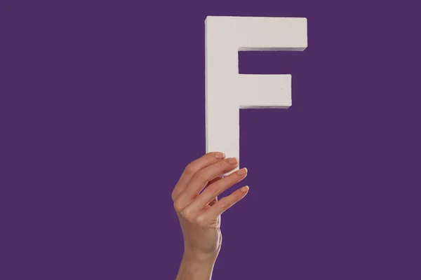 Γυναικείο χέρι που κρατά ψηλά το γράμμα f από το κάτω μέρος — Φωτογραφία Αρχείου