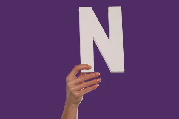 Kvinnlig hand som håller upp den bokstav n från botten — Stockfoto