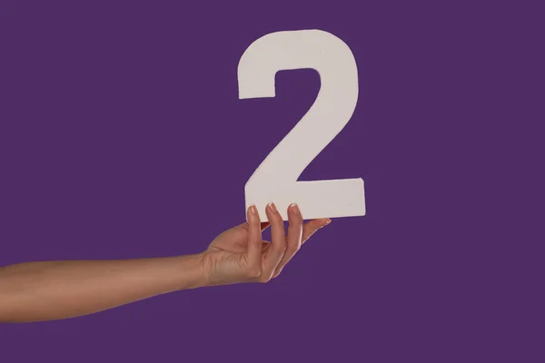Mão feminina segurando o número 2 da esquerda — Fotografia de Stock