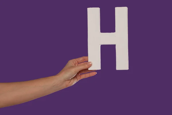 Женская рука держит букву H слева. — стоковое фото