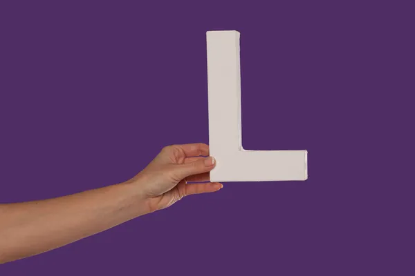 Mano femenina sosteniendo la letra L desde la izquierda — Foto de Stock