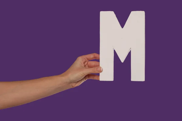 Mano femenina sosteniendo la letra M desde la izquierda — Foto de Stock