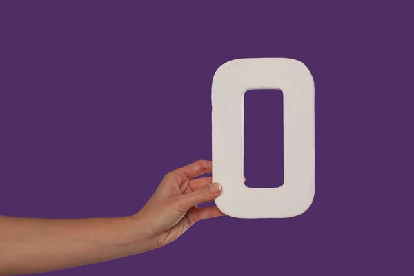 Female hand holding up the letter O from the left — Stock Photo, Image