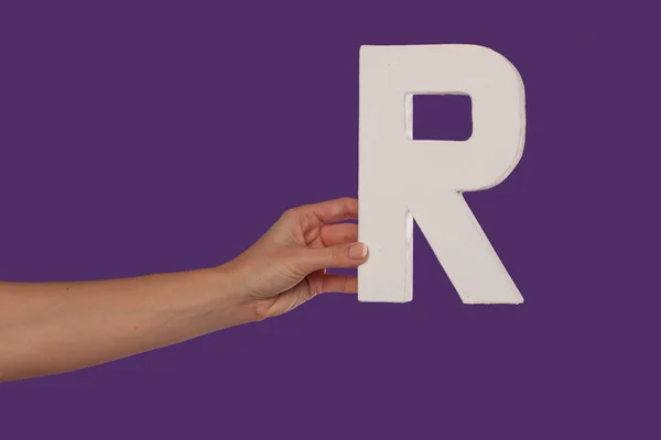 Kvinnlig hand som håller upp den bokstav r från vänster — Stockfoto