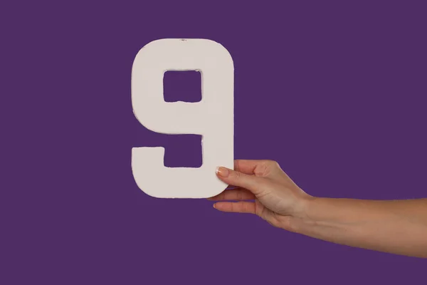 Mão feminina segurando o número 9 da direita — Fotografia de Stock