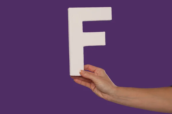 Mano femenina sosteniendo la letra F desde la derecha —  Fotos de Stock
