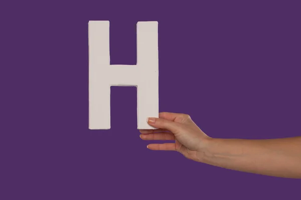 Female hand holding up the letter H from the right — Stock Photo, Image