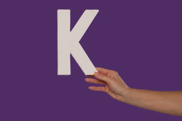 Mano femenina sosteniendo la letra K desde la derecha —  Fotos de Stock