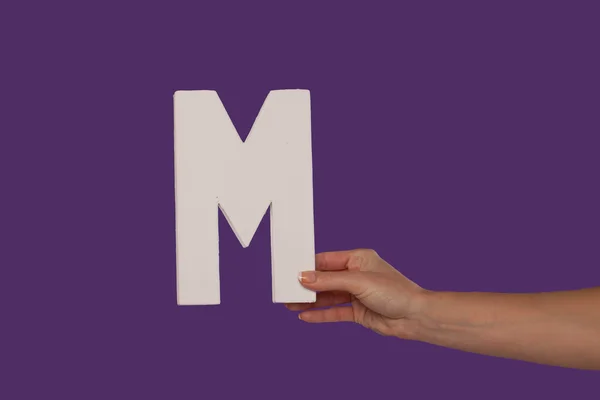 Γυναικείο χέρι που κρατά ψηλά το γράμμα m από το δικαίωμα — Φωτογραφία Αρχείου