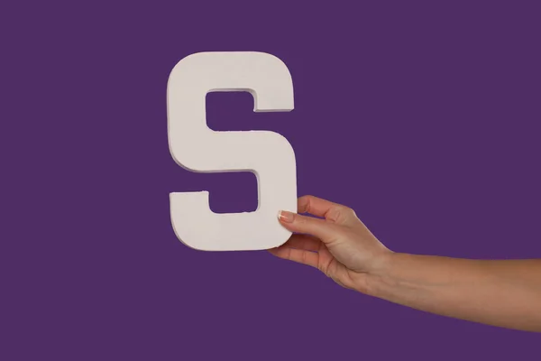Женская рука держит букву S справа — стоковое фото