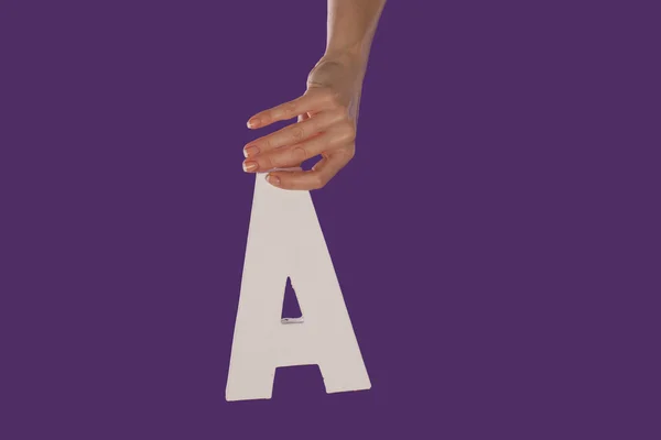 Weibliche Hand hält den Buchstaben a von oben — Stockfoto