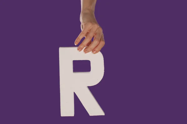 Mano femenina sosteniendo la letra R desde arriba — Foto de Stock