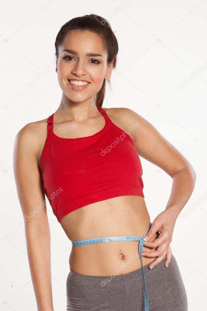 Woman measuring her waist with a smile