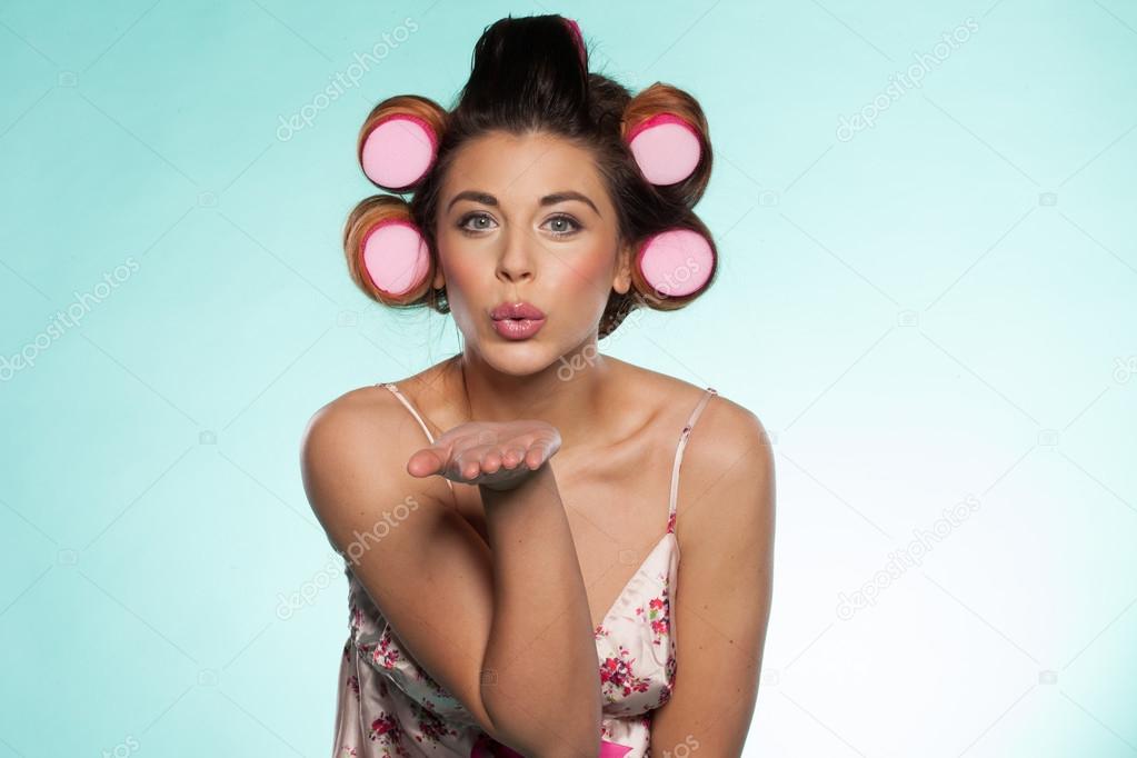 Sexy woman in curlers blowing a kiss