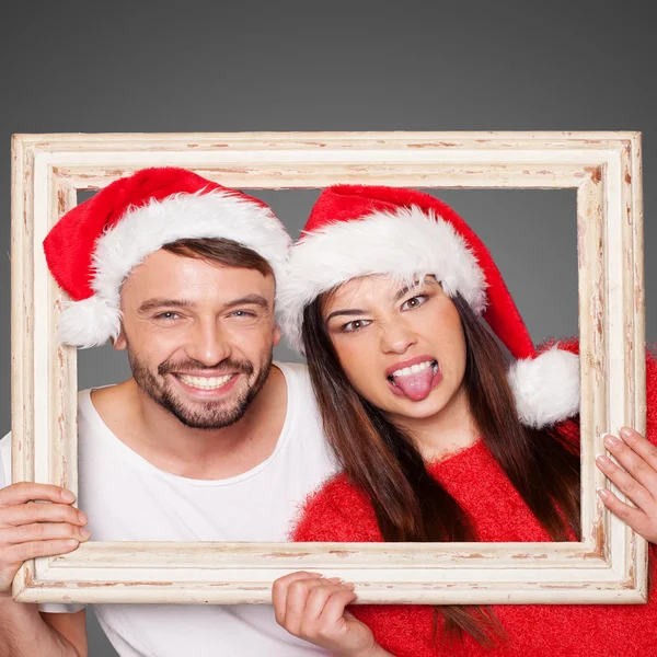 Paar schaut mit Weihnachtsmütze durch Rahmen — Stockfoto