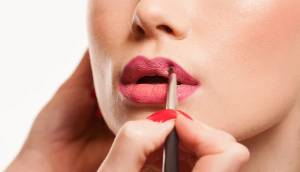 Estilista aplicando gloss labial para uma jovem mulher — Fotografia de Stock