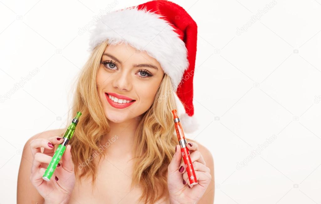 Beautiful woman in a Santa hat with e-cigarettes