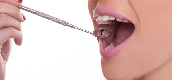 Mulher com um espelho dental exibindo os dentes — Fotografia de Stock