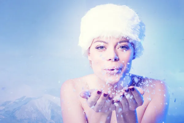 Hermosa mujer joven soplando nieve de invierno — Foto de Stock