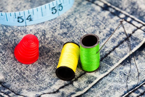 Cotton, needle, and a thimble on denim jeans — Stock Photo, Image