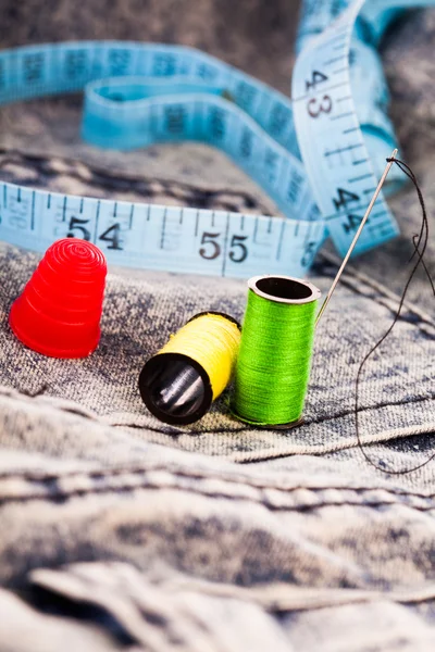 Aiguille, bobines de coton et ruban adhésif sur tissu denim — Photo