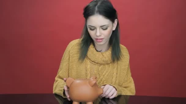 Pretty young woman shaking her piggy bank — Stock Video