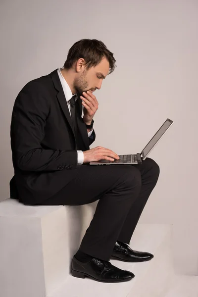 Empresário sentado em uma escada trabalhando em um laptop — Fotografia de Stock