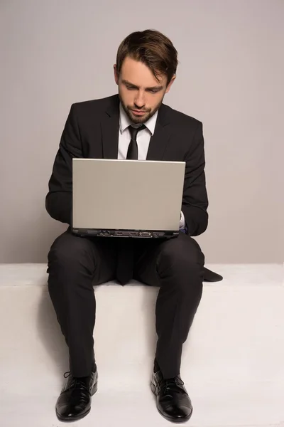 Businessman sitting on a stair working on a laptop — Stock Photo, Image