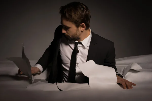 Handsome young bearded businessman climbing out of a hole — Stock Photo, Image