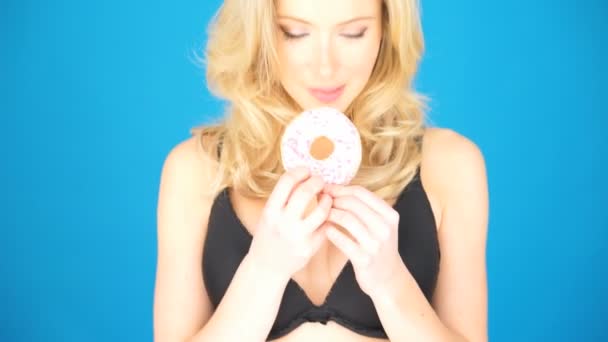 Schöne blonde Frau isst einen großen Donut — Stockvideo