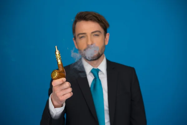 Businessman with e-cigarette wearing suit and tie on blue — Stock Photo, Image