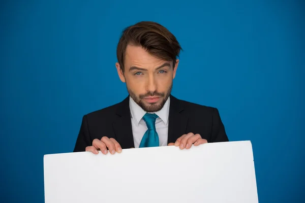 Empresario sosteniendo cartel en blanco — Foto de Stock