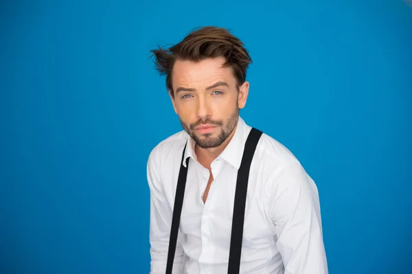 Hombre guapo en azul vistiendo camisa blanca y frenos — Foto de Stock