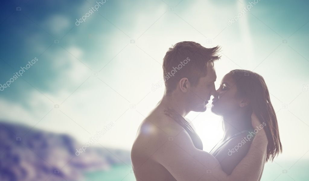 Young couple kissing backlit by the sun