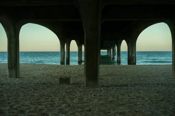 Underneath a marine pier at low tide — Stock Photo, Image