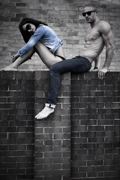 Jeune couple posant sur le mur de béton — Photo