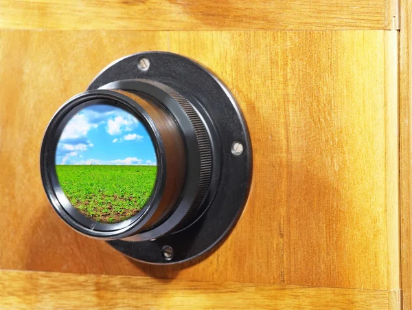 Kameralinse mit blauem Himmel und grüner Grasspiegelung. — Stockfoto