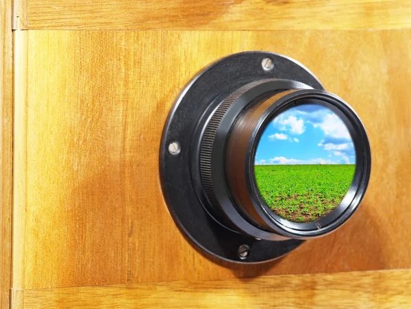 Camera lens with blue sky and green grass reflection. — Stock Photo, Image