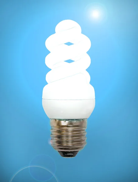 Lampe à économie d'énergie sur fond bleu . — Photo