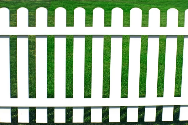 Зеленая трава с другой стороны за белым забором . — стоковое фото