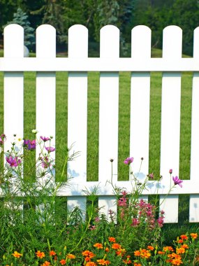 White fence on green grass and flowers. clipart