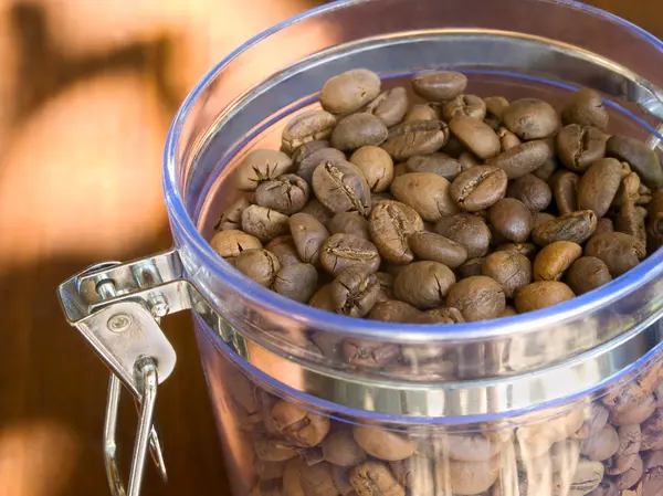 Aptitretande kaffebönor i glasbehållare. — Stockfoto
