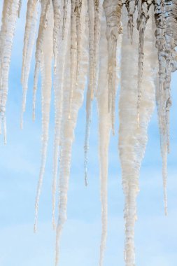 Mavi gökyüzü arkaplanındaki donmuş buz saçakları yakından çekildi.