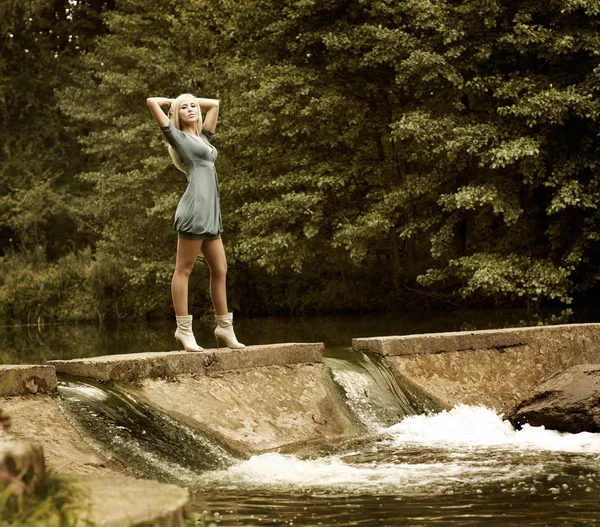 Mooie blonde vrouw permanent in de buurt van de waterval — Stockfoto