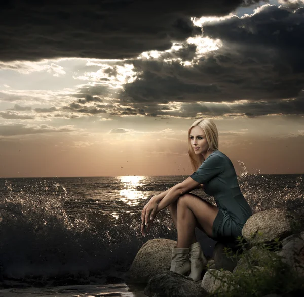 Mooie blonde vrouw zitten in de buurt van de zee — Stockfoto