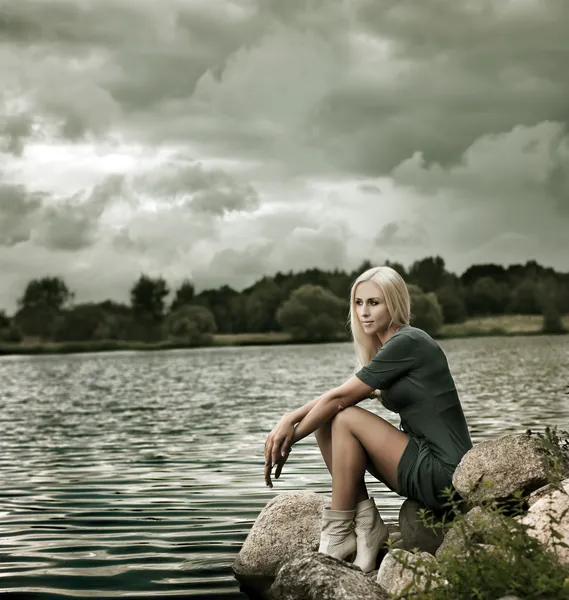 Bella donna bionda seduta vicino all'acqua — Foto Stock