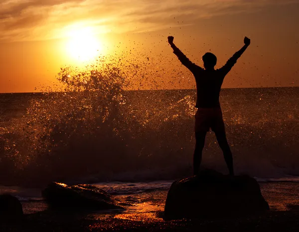 Człowiek w wzburzonym morzu na zachód słońca — Zdjęcie stockowe