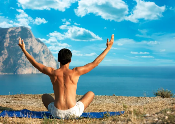 Hombre haciendo yoga en el mar y las montañas — Foto de Stock