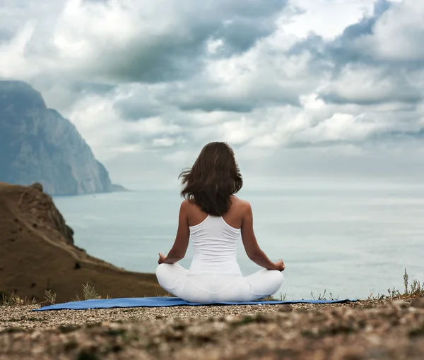 Mujer haciendo yoga en el mar y las montañas — Foto de Stock