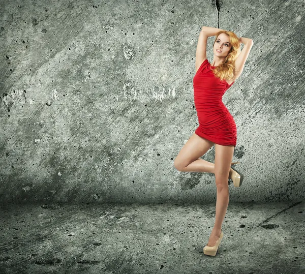 壁の背景に赤いドレスで美しい女性 — ストック写真
